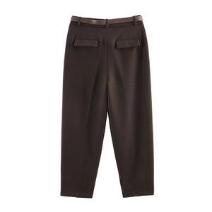 Dettaglio di pantaloni marroni a vita alta con cintura coordinata e tasche posteriori a patta