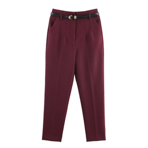 Dettaglio dei pantaloni bordeaux a vita alta con sottile cintura nera e fibbia dorata