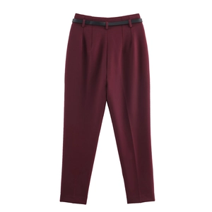 Dettaglio dei pantaloni rosso vino a vita alta con sottile cintura nera in PU e pieghe