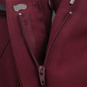 Dettaglio dei pantaloni bordeaux con chiusura a zip e gancio in metallo sulla vita