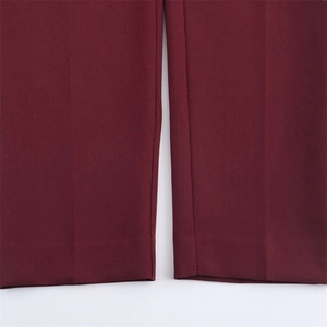 Dettaglio ravvicinato dell'orlo dei pantaloni bordeaux con cuciture piatte e trama del tessuto