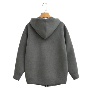 Detail view of the back of a loose dark gray zip-up hoodie with ribbed hem on a hanger