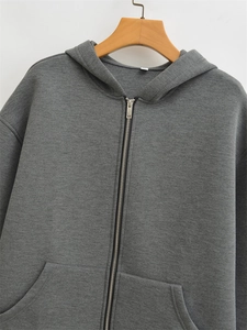 Detail of dark grey zip-up hoodie featuring a silver metal zipper and kangaroo pocket