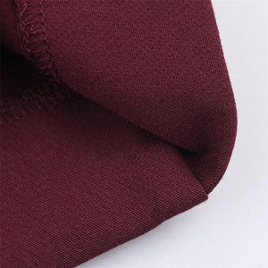 Dettaglio dei pantaloni in maglia rosso scuro con cuciture e trama del tessuto a vista