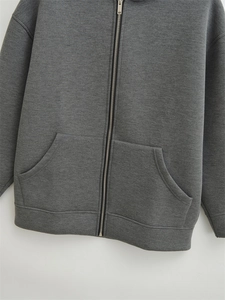 Detail view of the metal zipper and ribbed cuffs on a dark grey oversized hoodie