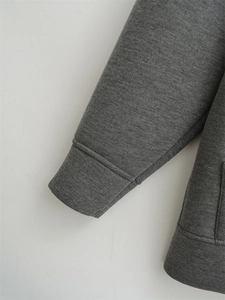 Detailed macro view of the grey cotton blend knit fabric and ribbed elastic cuffs on the hoodie
