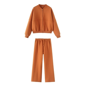 Detail of orange zip-up sweatshirt and straight-leg trousers with drawstring waist