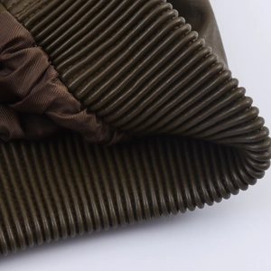 Detail of dark olive green faux leather jacket showing accordion pleats and satin lining