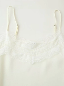 Close-up of adjustable spaghetti straps and layered lace neckline on a cream satin top