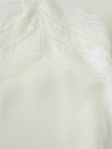 Detailed close-up of delicate white layered lace embroidery and floral texture