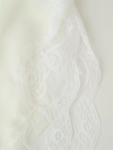 Detailed macro view of delicate white floral lace fabric with smooth satin finish