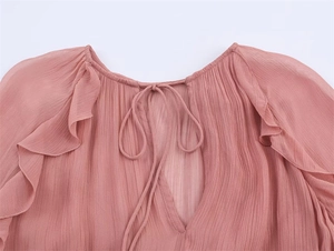 Detail of pink chiffon top featuring ruffled layers and a tied V-neckline texture