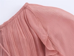 Detailed macro view of pink chiffon pleated fabric with ruffled hem and fine stitching