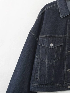 Dettaglio giacca in denim blu scuro con cuciture a contrasto e tasche sul petto con automatici
