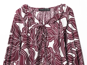 Detail of the V-neckline with ruffles and burgundy floral print on long sleeve top
