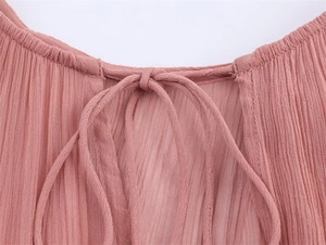 Detail of pink pleated fabric dress showing the lace-up neck design and ruffles