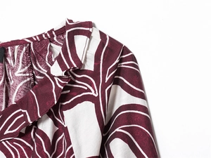 Detail of ruffle neckline on burgundy and cream leaf print blouse with fine stitching