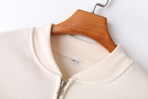 Close-up of cream white zip-up jacket with ribbed collar and silver metal zipper detail