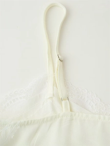 Detail showing white satin fabric with delicate floral lace trim and adjustable straps