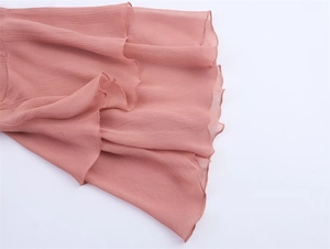 Detail shot of coral pink tiered ruffle sleeves with a delicate crinkle chiffon texture