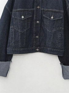 Dettaglio ravvicinato della giacca di jeans blu scuro con cuciture a contrasto e bottoni
