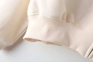 Macro view of ribbed cuff detail and soft fleece lining on cream sweatshirt