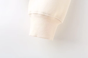 Macro view of ribbed cuffs on cream-colored zip jacket with soft knitted texture