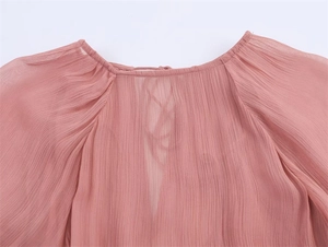 Close-up of pink chiffon dress neckline with delicate pleats and sheer textured fabric
