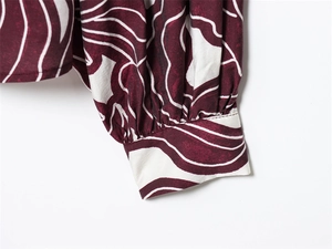 Detail of ruffle sleeve cuff on burgundy blouse with white wave print fabric