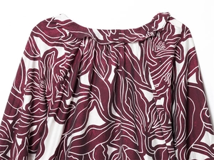 Detail of ruffled round neckline with wine red floral print on soft fabric