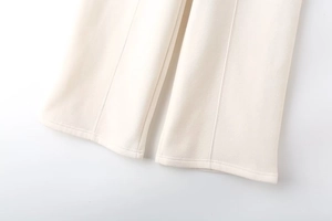 Detailed macro view of cream-colored trousers featuring vertical seams and thick fabric