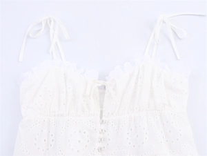 Detail van witte camisole met broderie anglaise, kantafwerking en parelknopen