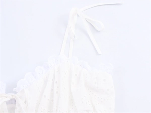 Detail van witte katoenen camisole met fijn broderie-borduurwerk en strikjes op de schouders