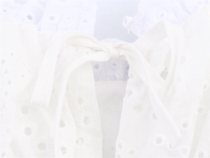 Detailopname van wit broderie anglaise en de fijne strik op een zomerse top