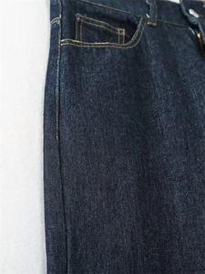 Dettaglio ravvicinato di jeans blu scuro a vita alta con cuciture a contrasto arancioni
