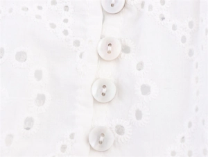 Macro-opname van witte broderie anglaise stof met parelmoer knopen aan de voorzijde