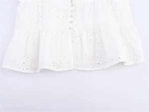 Detail van de witte Broderie Anglaise top met borduurwerk en kleine ronde witte knopen
