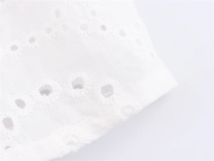 Gedetailleerde close-up van wit geborduurd bloemenpatroon op de stof van de camisole top