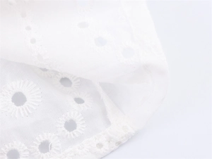 Macrodetail van witte borduurstof met gaatjes en nette stiksels op de zomerse camisole