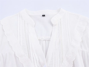 Detailaufnahme der weißen Bluse mit Spitzenstickerei, Stehkragen und Biesen-Details