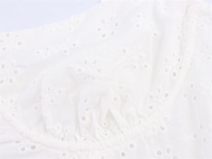 Detailopname van wit broderie anglaise en bloemmotieven op een midi-jurk