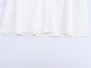 Detailaufnahme der weißen Bluse mit Laternärmeln, Wellenstickerei und Knopfleiste