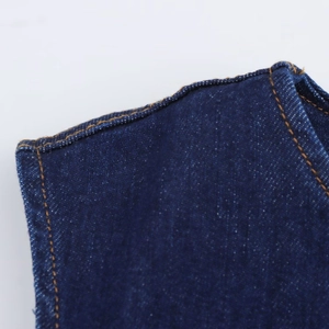 Gros plan sur le denim bleu foncé avec des surpiqûres orange sur la robe midi