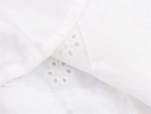 Detail van wit broderie anglaise borduurwerk op hoogwaardige zomerse katoenen stof