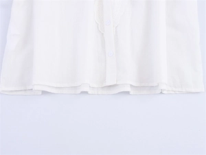 Detailansicht der weißen Bluse mit Spitzenstickerei, Knöpfen und eleganten Ärmeln