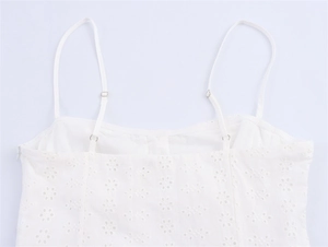 Detail van witte broderie anglaise stof met verstelbare spaghettibandjes en zijrits