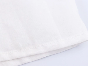 Nahaufnahme der reinweißen Bluse mit hochwertigen Doppelnähten und feiner Stoffstruktur