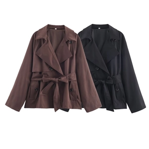 Detailweergave van korte trenchcoats in bruin en zwart met brede revers en een tailleriem