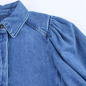 Détail des manches bouffantes et du col sur une chemise en jean bleu moyen au style rétro