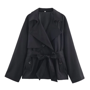 Detailopname van een zwarte korte trenchcoat met double-breasted knopen en een tailleriem